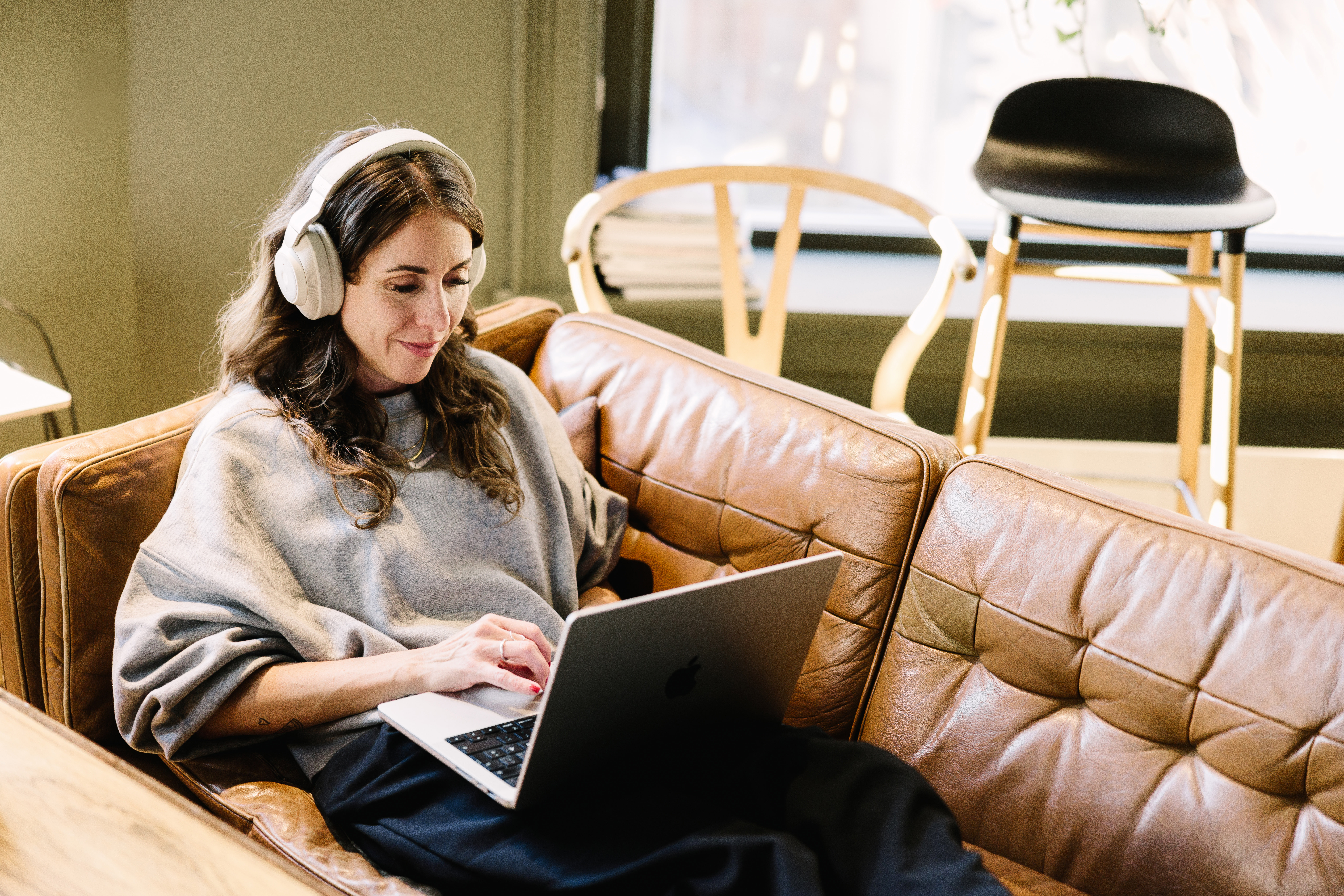 Kvinne som sitter i sofa og oppdaterer sine nettsider på en mac.