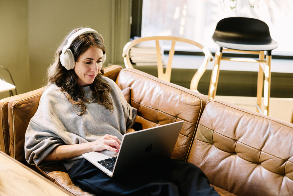Kvinne som sitter i sofa og oppdaterer sine nettsider på en mac.